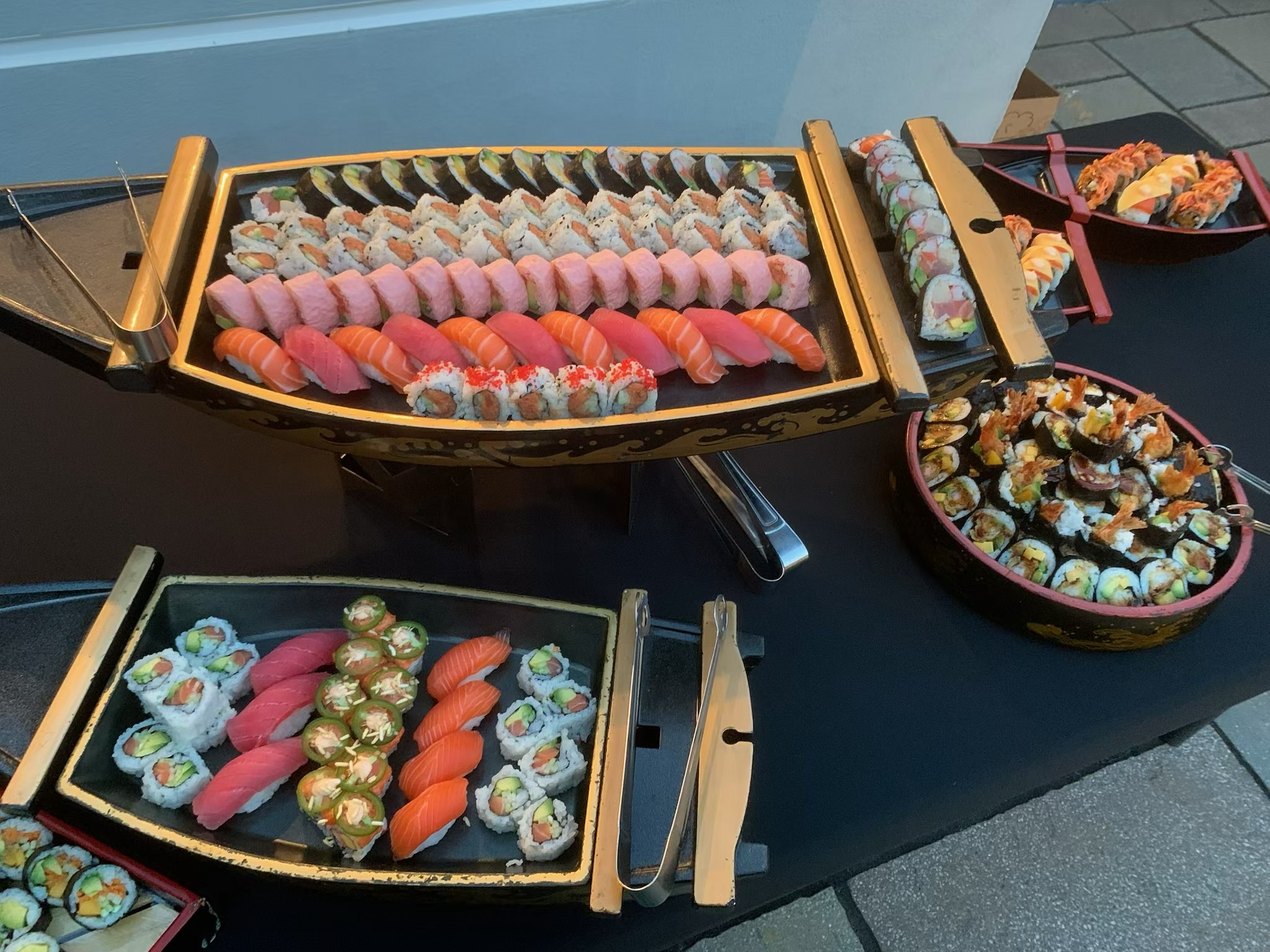 Full sushi platters display at elegant wedding reception with chandeliers and guests